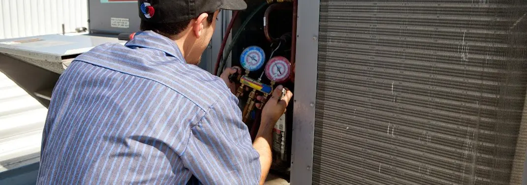 HVAC technician servicing a condenser unit in Heeia